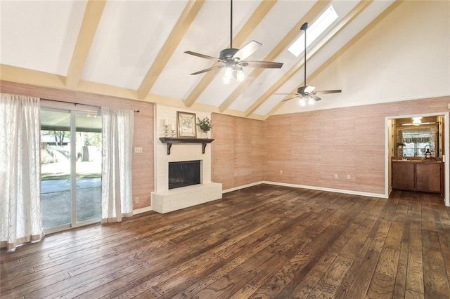 unfurnished living room with a skylight, dark wood finished floors, beamed ceiling, a fireplace, and high vaulted ceiling