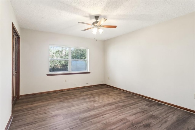 spare room featuring dark wood-type flooring, a textured ceiling, and baseboards