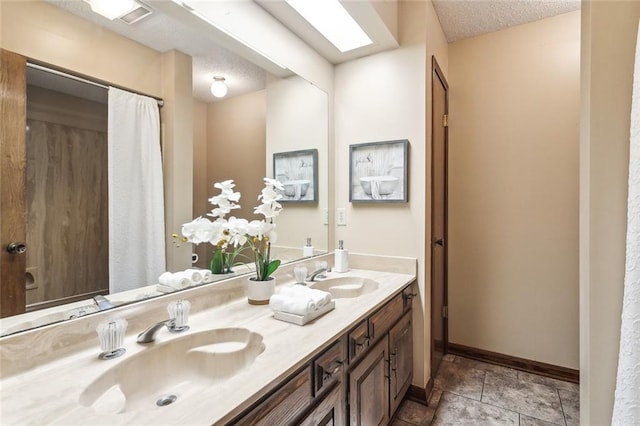 bathroom featuring double vanity, a textured ceiling, baseboards, and a sink