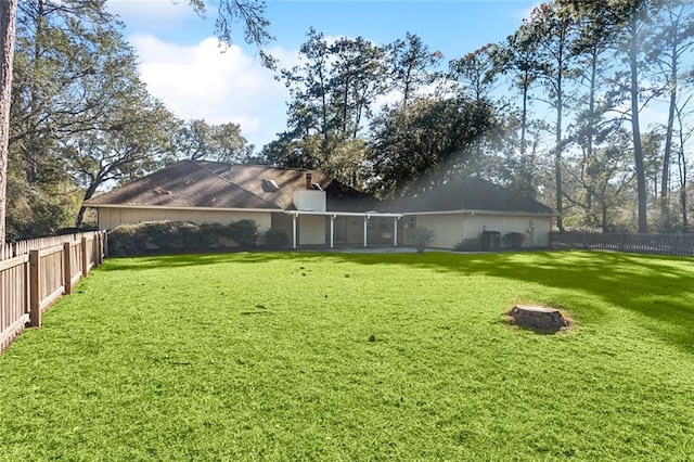 rear view of house featuring a fenced backyard and a yard