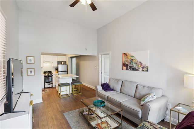 living area with dark wood-style flooring, ceiling fan, a towering ceiling, and baseboards