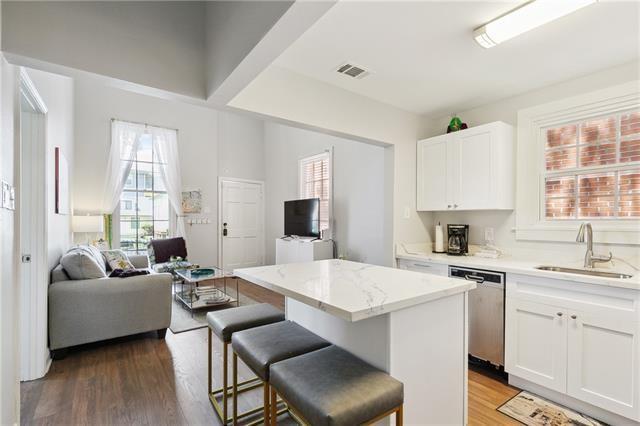 kitchen featuring stainless steel dishwasher, open floor plan, white cabinetry, a kitchen island, and a sink