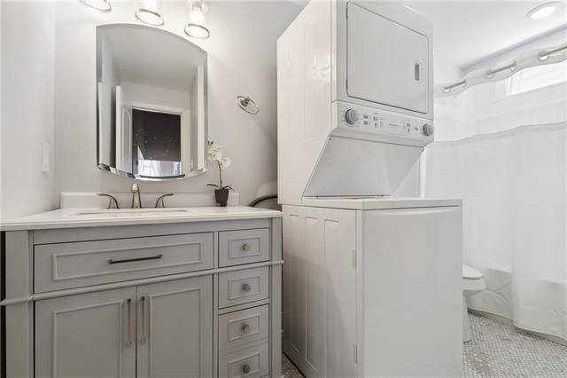 full bathroom featuring toilet, shower / tub combo, stacked washer / dryer, and vanity