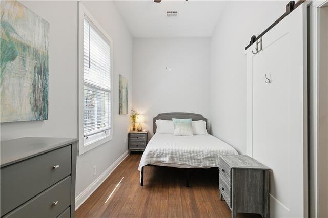 bedroom featuring dark wood-style floors, visible vents, baseboards, and a barn door