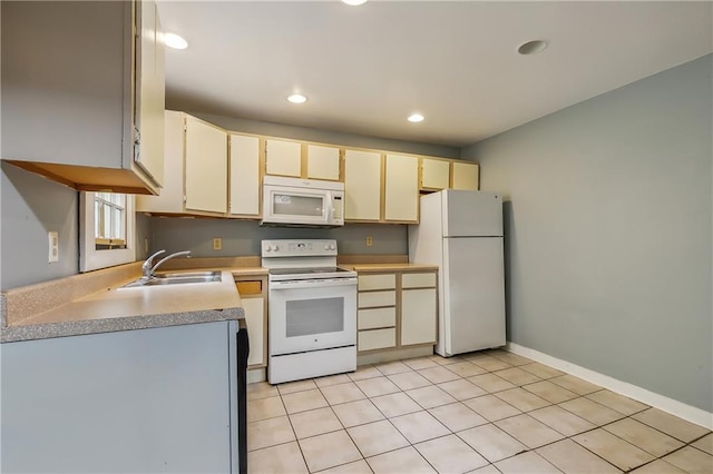 kitchen featuring white appliances, light countertops, cream cabinetry, a sink, and light tile patterned flooring