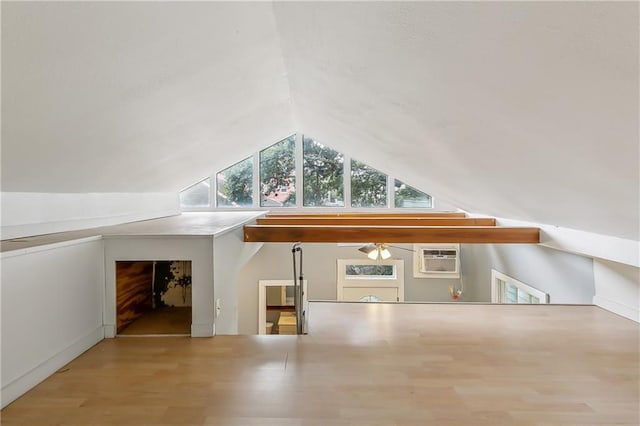 additional living space with vaulted ceiling, an AC wall unit, and wood finished floors