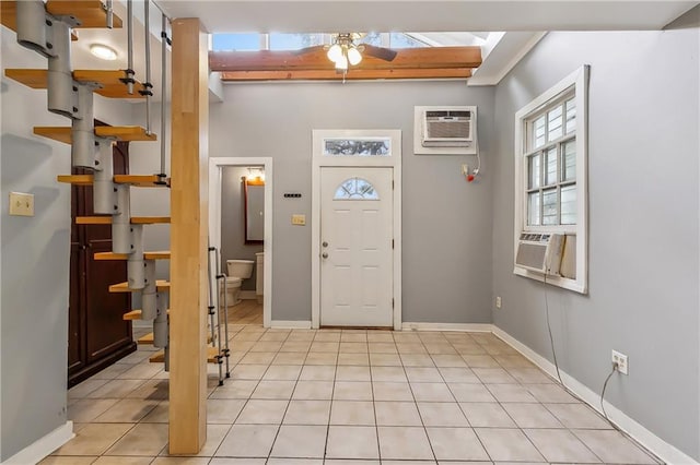 entrance foyer with light tile patterned floors, ceiling fan, cooling unit, a wall mounted air conditioner, and baseboards