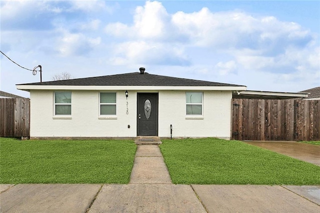 view of front of property featuring fence, a front lawn, and brick siding