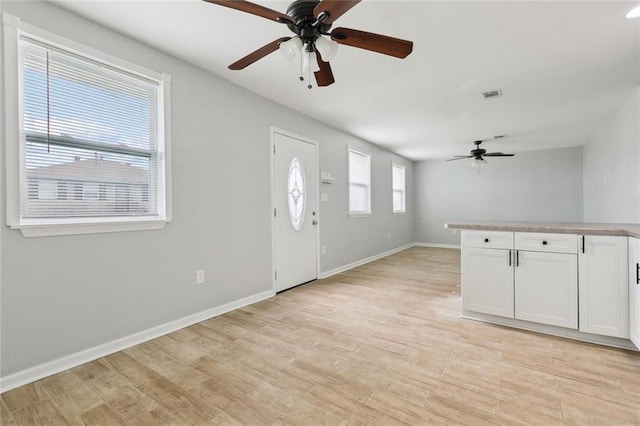 foyer with light wood-style floors, visible vents, and baseboards