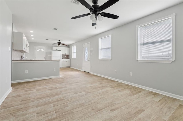 unfurnished living room featuring light wood-type flooring, baseboards, and recessed lighting