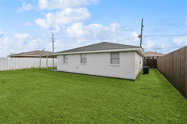 rear view of property featuring brick siding, a fenced backyard, central AC unit, and a yard