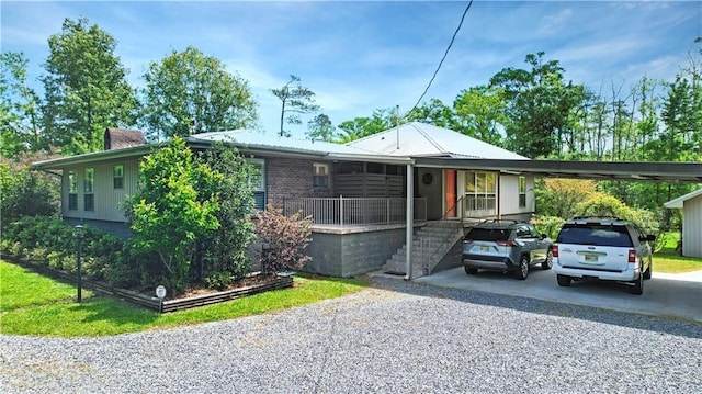 single story home with gravel driveway, metal roof, and a carport