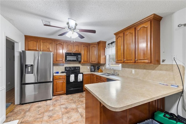 kitchen featuring ceiling fan, a peninsula, light countertops, brown cabinets, and black appliances