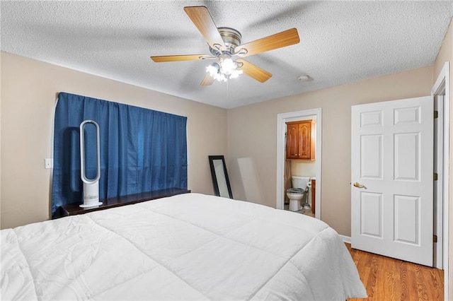 bedroom featuring a textured ceiling, ceiling fan, ensuite bath, and wood finished floors