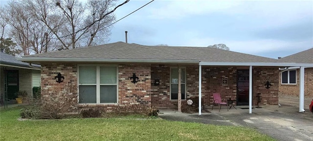 view of front of house featuring a shingled roof, a front yard, and brick siding