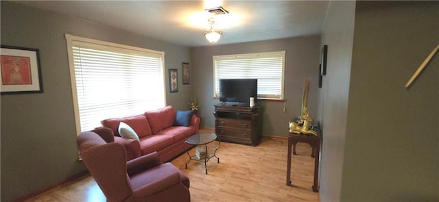 living room featuring light wood finished floors, visible vents, and baseboards