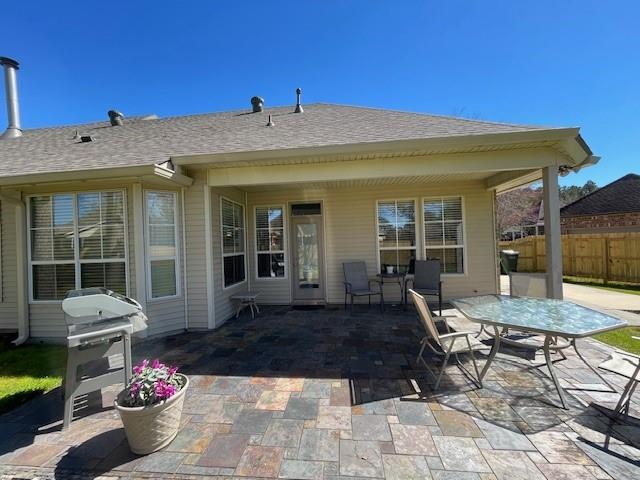 rear view of house with a patio area, fence, and roof with shingles