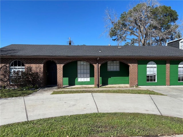 view of front of property with a shingled roof and brick siding