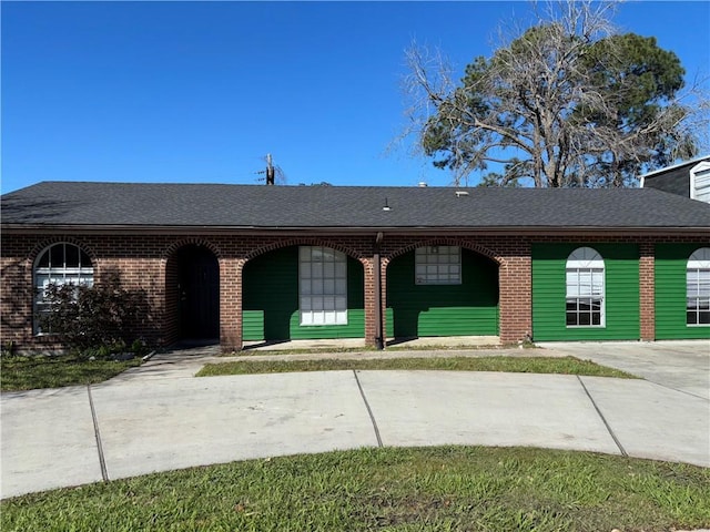 view of front of home featuring brick siding and roof with shingles