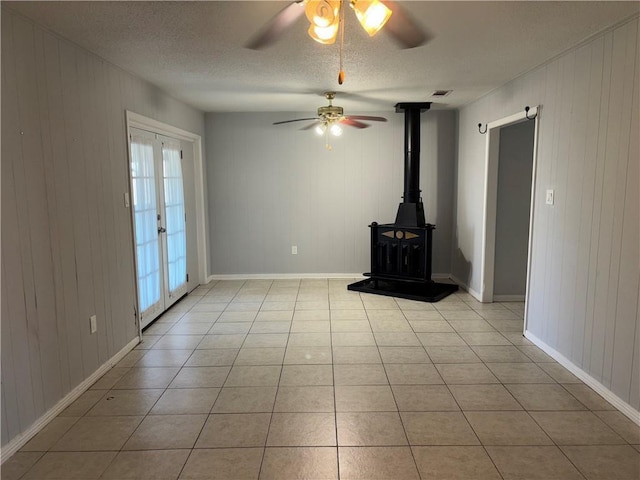 unfurnished living room featuring visible vents, a wood stove, a textured ceiling, french doors, and light tile patterned flooring