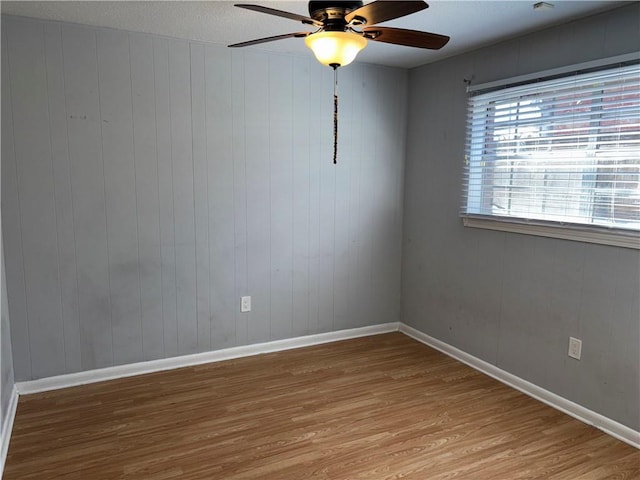 spare room featuring light wood-style flooring, baseboards, and a ceiling fan