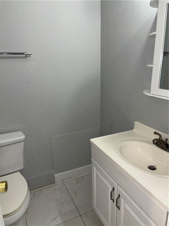 bathroom featuring marble finish floor, baseboards, vanity, and toilet