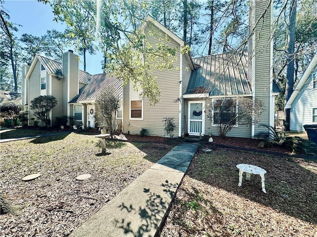 view of front of home with a standing seam roof, metal roof, and a chimney