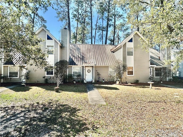 view of front of home with a chimney, a front lawn, and metal roof