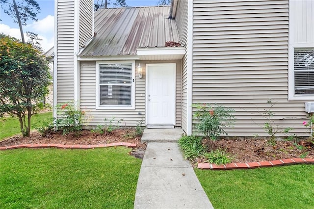 doorway to property with metal roof, a yard, and a chimney