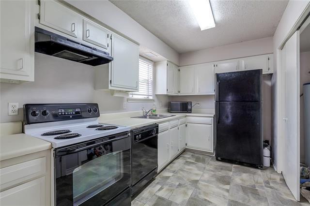 kitchen with white cabinets, under cabinet range hood, light countertops, black appliances, and a sink