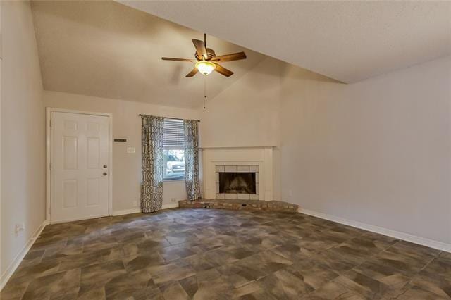 unfurnished living room featuring lofted ceiling, baseboards, a fireplace with raised hearth, and a ceiling fan