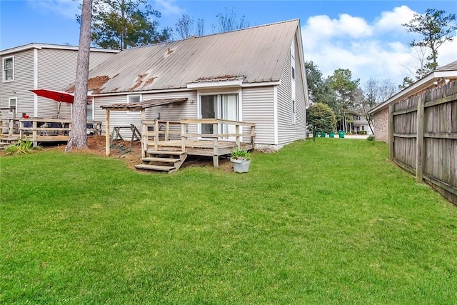 back of property with a deck, metal roof, a yard, and fence