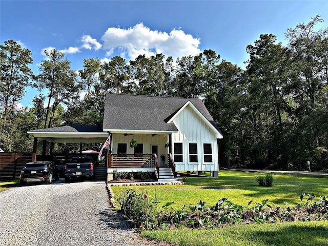 view of front of house featuring roof with shingles, board and batten siding, a front yard, a carport, and driveway