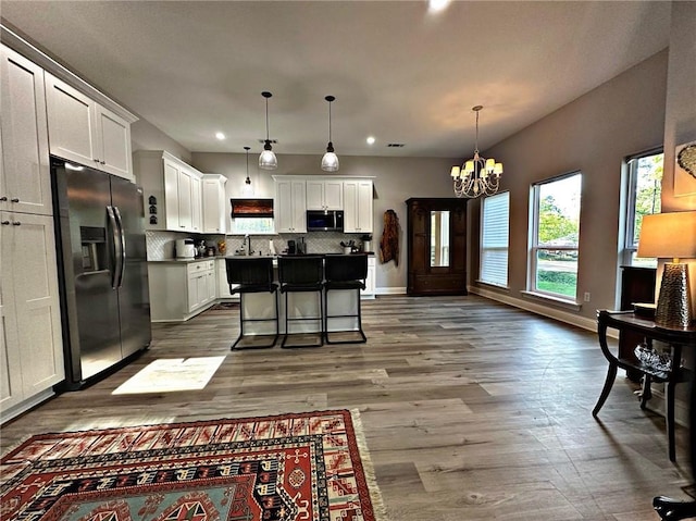 kitchen with a breakfast bar, white cabinetry, stainless steel fridge with ice dispenser, backsplash, and a center island