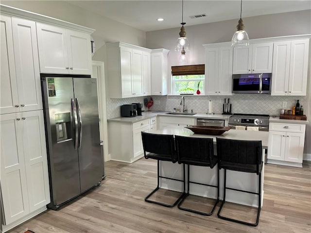 kitchen featuring a kitchen island, appliances with stainless steel finishes, a kitchen breakfast bar, and pendant lighting