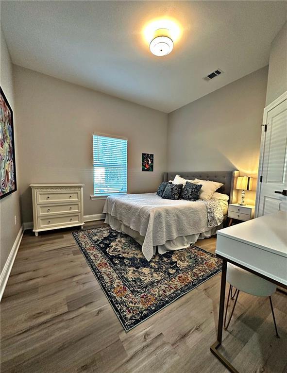 bedroom with dark wood-style floors, visible vents, and baseboards