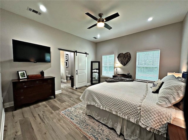 bedroom featuring a barn door, recessed lighting, visible vents, baseboards, and light wood finished floors