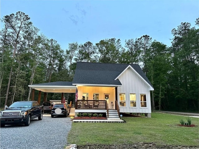 modern farmhouse style home with a shingled roof, covered porch, board and batten siding, a front yard, and driveway