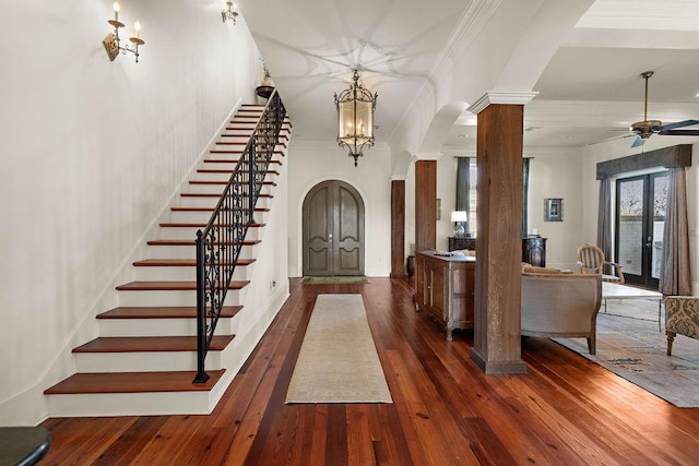 foyer entrance with arched walkways, dark wood finished floors, stairs, french doors, and ornate columns