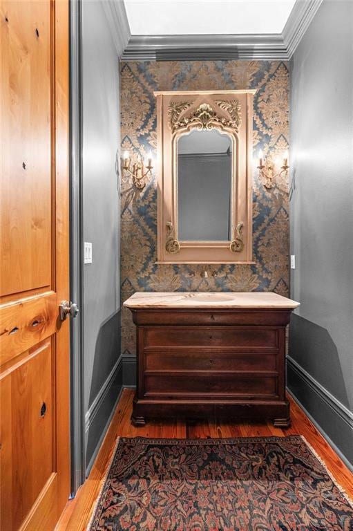 bathroom featuring ornamental molding, vanity, and wallpapered walls