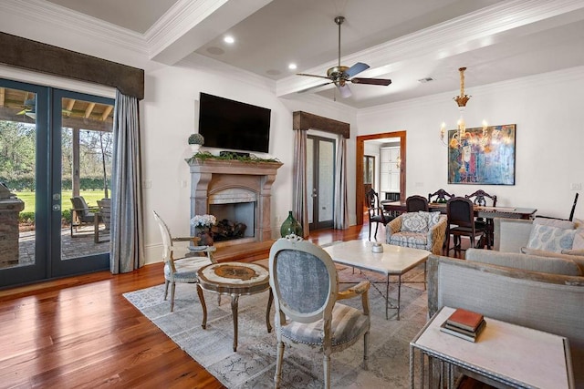 living area featuring visible vents, a fireplace with raised hearth, ornamental molding, wood finished floors, and french doors