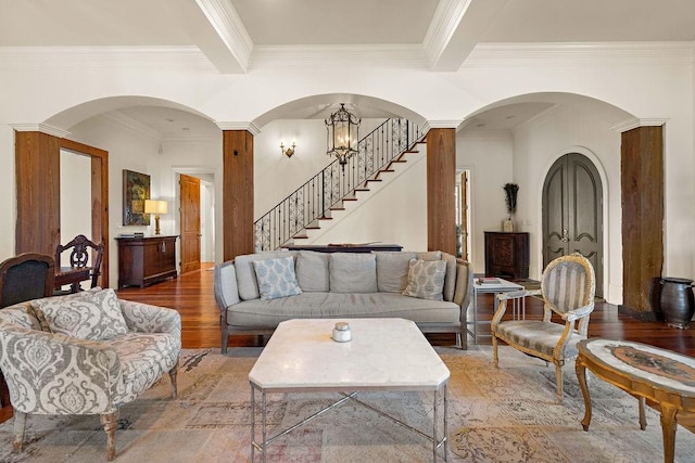 living room with beam ceiling, crown molding, stairway, wood finished floors, and a chandelier