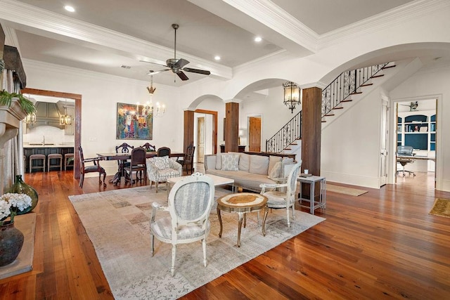 living room with hardwood / wood-style floors, stairs, ceiling fan with notable chandelier, crown molding, and recessed lighting