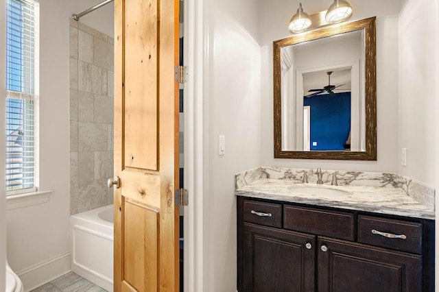 bathroom with washtub / shower combination, vanity, baseboards, and a ceiling fan