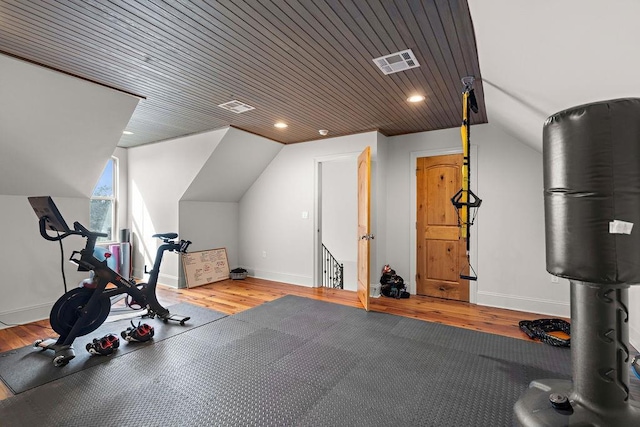 exercise room featuring vaulted ceiling, light wood-style flooring, visible vents, and baseboards