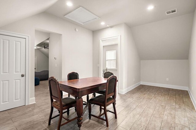 dining area featuring visible vents, attic access, light wood-style floors, vaulted ceiling, and baseboards