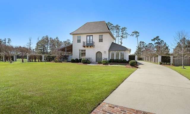 view of front of house with a front yard, driveway, fence, and stucco siding