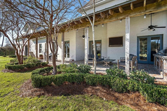 exterior space featuring a ceiling fan, a patio area, french doors, and brick siding