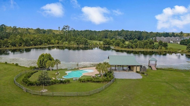 view of dock with a water view, a yard, and a forest view