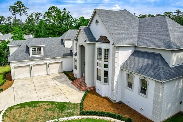 view of front facade featuring brick siding, an attached garage, concrete driveway, and roof with shingles